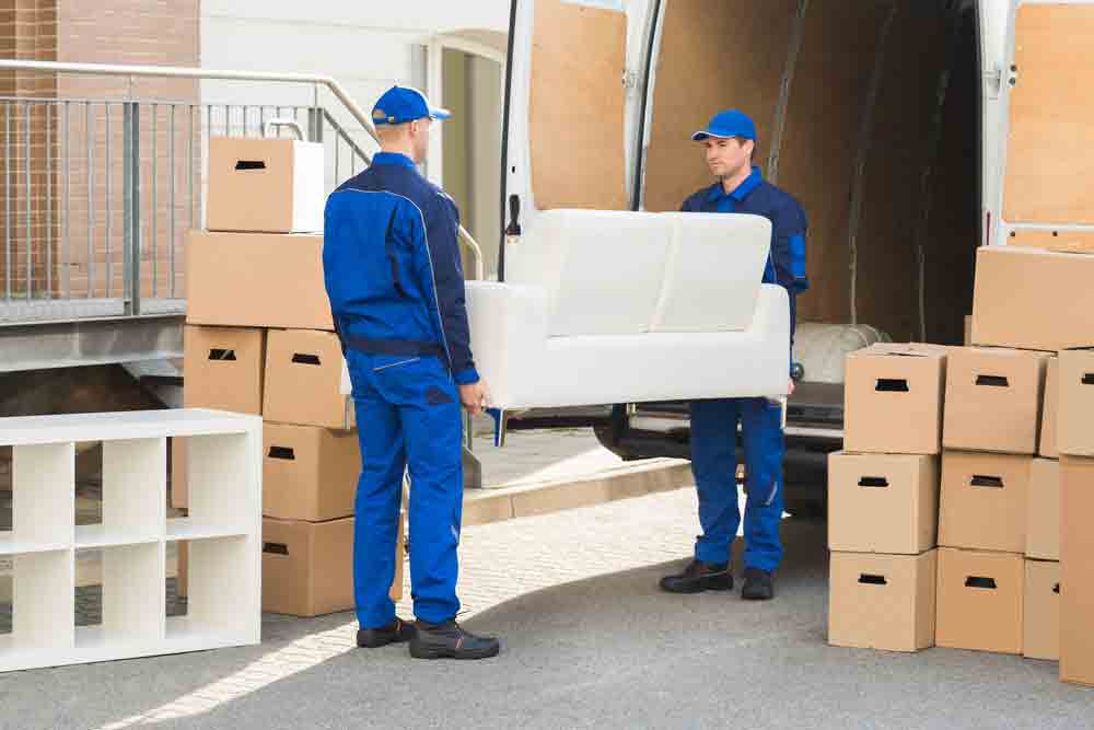 Two Men Carrying Sofa Going To The Truck — Furniture removalists in Newcastle, NSW