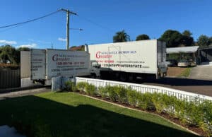 Two Removalist Trucks Parked In Front Of A House